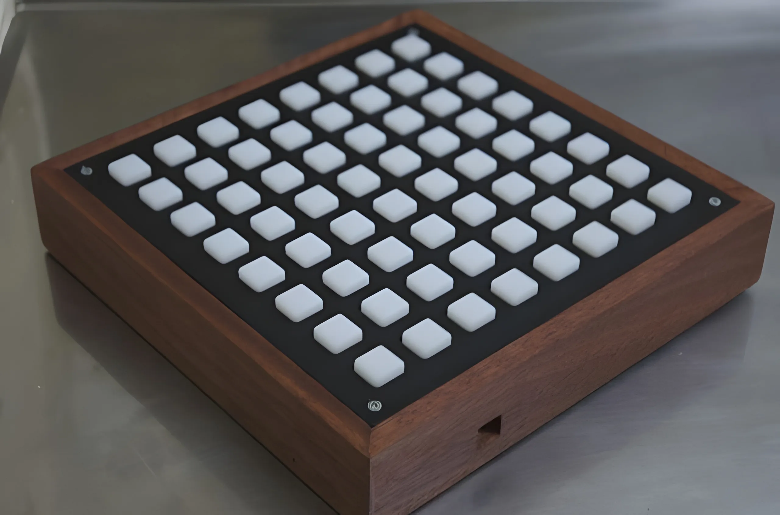 The same grid finished in a walnut enclosure, photographed on a brushed steel bench